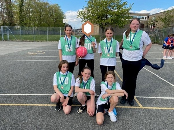 Students in green bibs pose with their medals after playing Netball