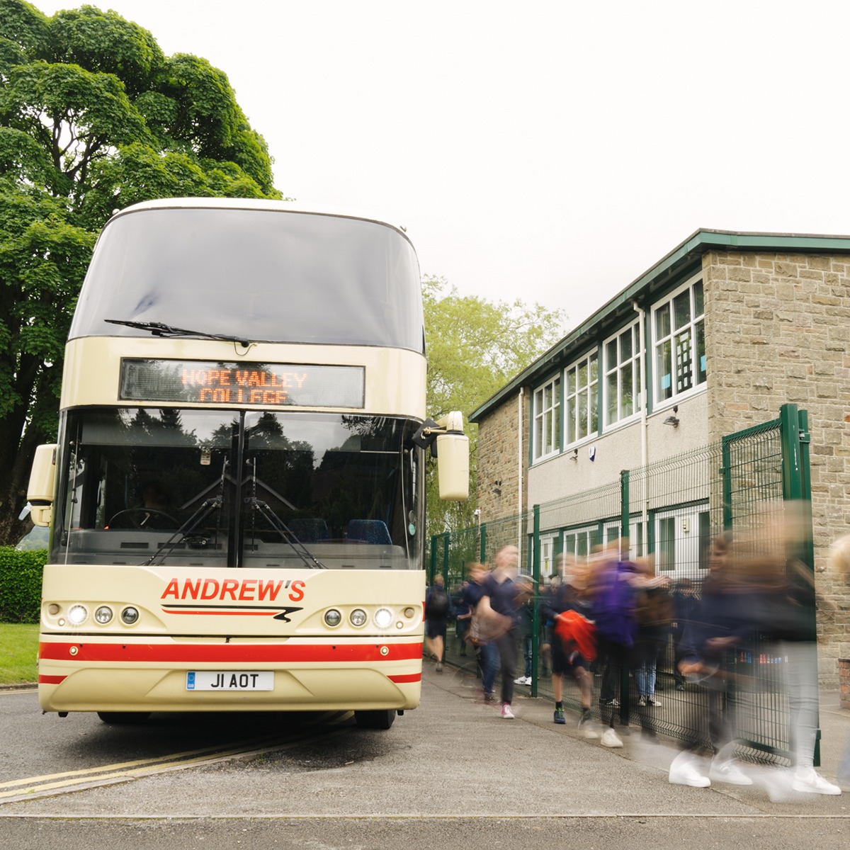 Image of an Andrews Coach with students entering the school site