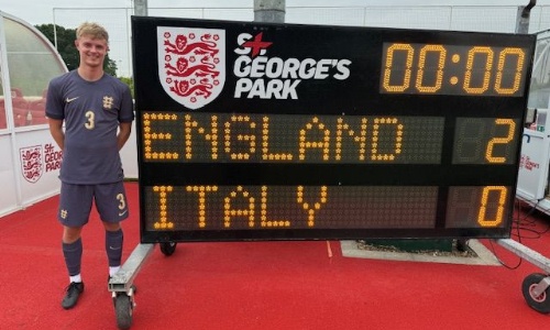 Trainee teacher at St George's Park standing next to a score board which reads England 2, Italy 0