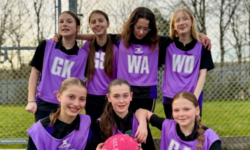 Year 7 Netball Team in purple bibs, smiling on the court